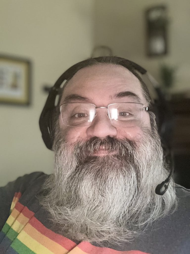 Jason King-Lowe, founder of Gymnarctos Studios, in headset and rainbow shirt—bringing practical, human-centered software solutions to small businesses.
