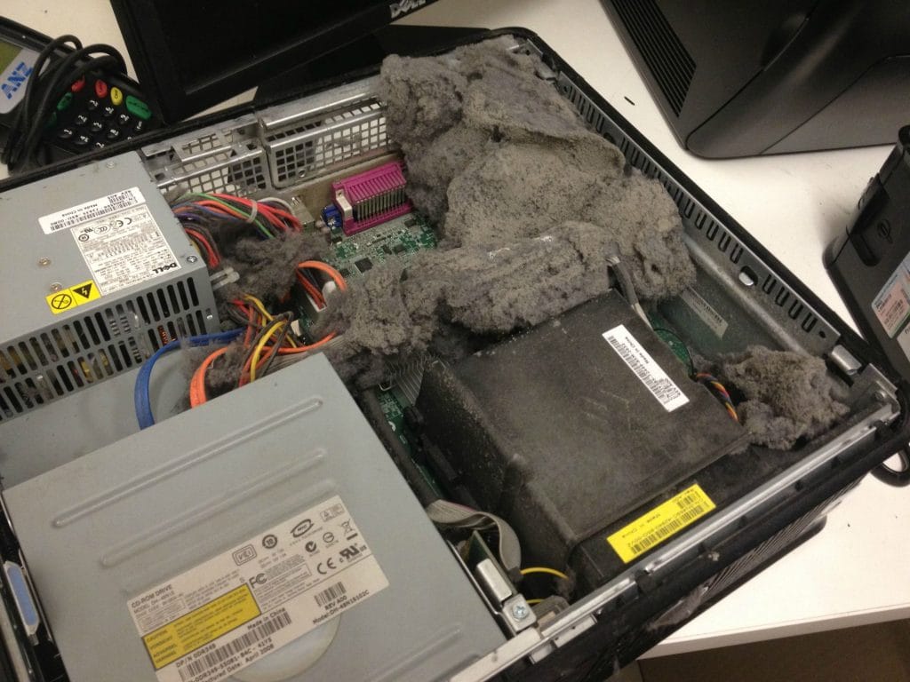 Interior of a computer case with a pat of dust covering the power supply and fan, demonstrating what happens when you don't clean your tech.